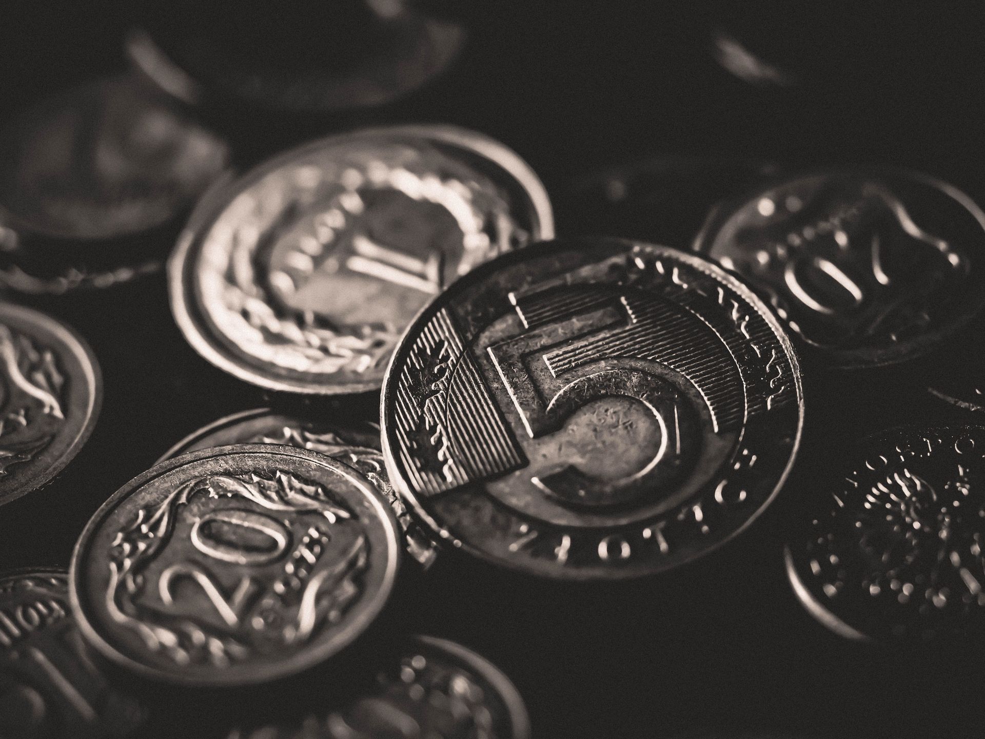 Detailed black and white close-up of assorted coins in grayscale.