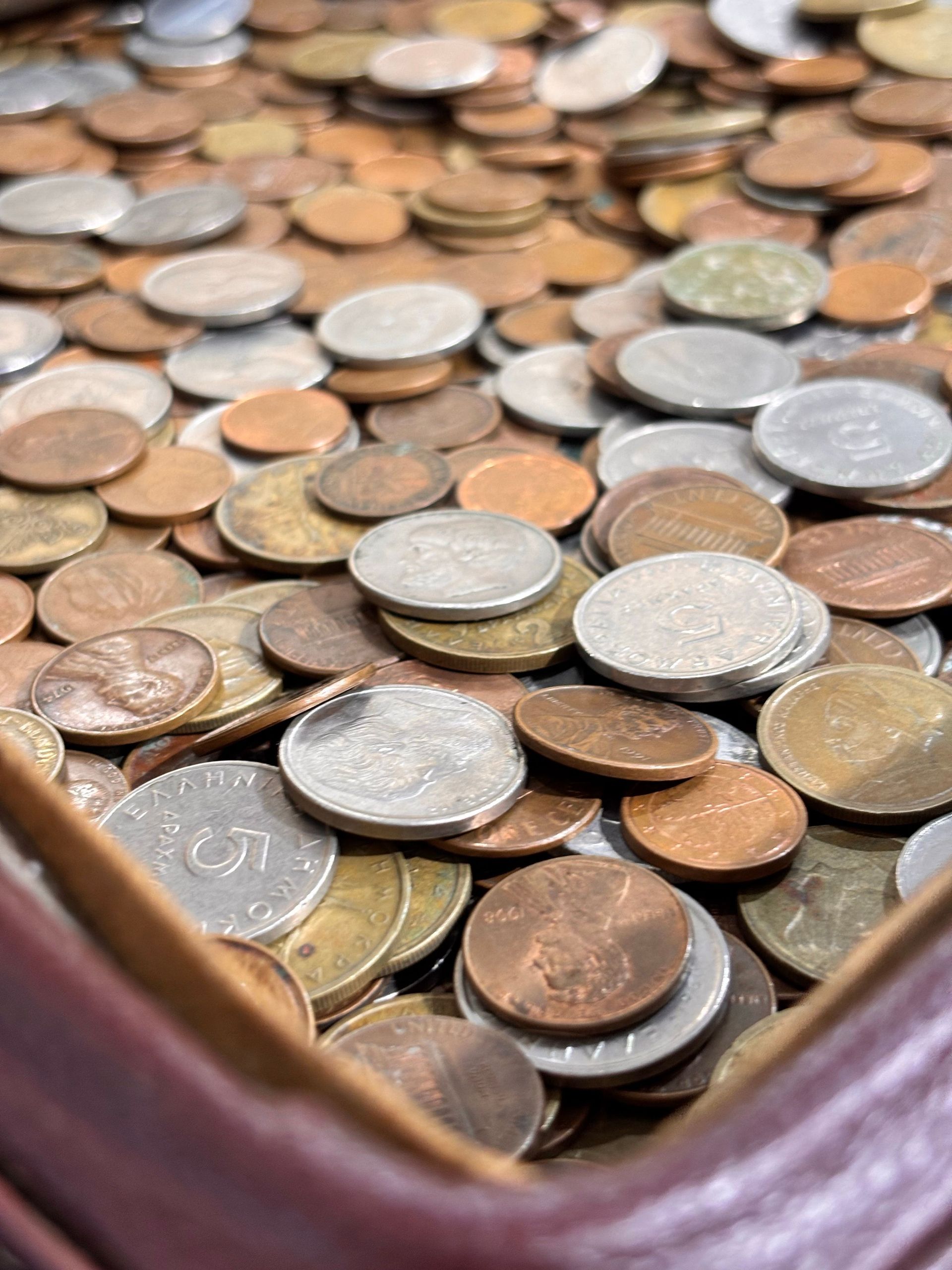 A variety of international coins scattered inside a leather purse, emphasizing diversity.